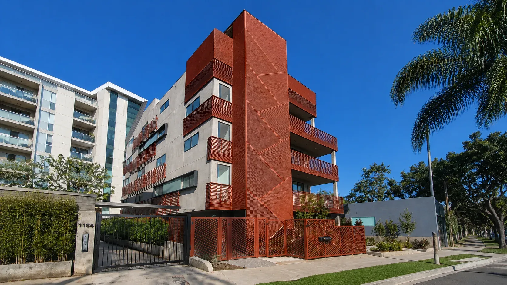 A four-storey multi-unit building with aluminum balcony railings on every floor and a matching aluminum gate at street level