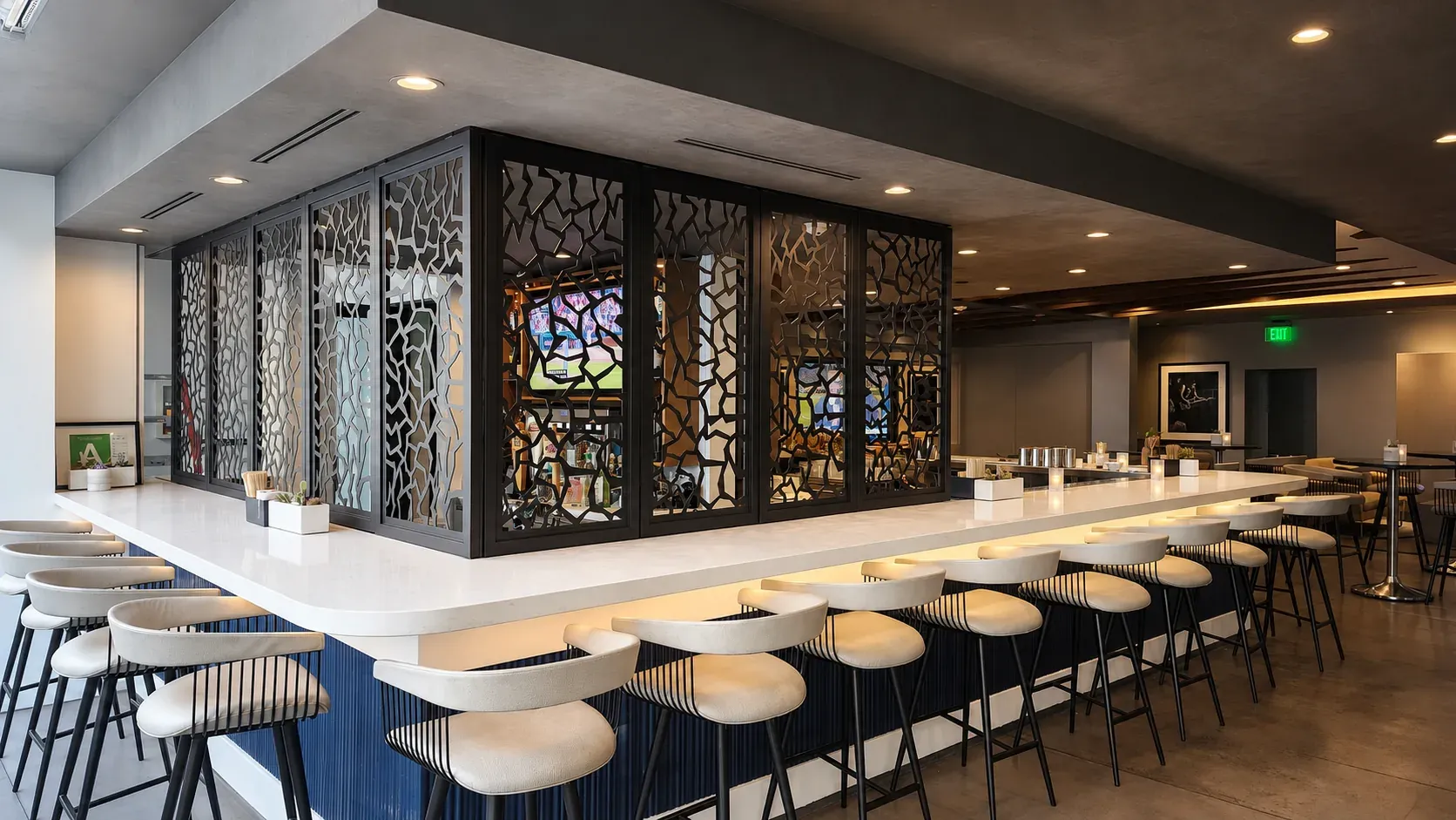 A hotel bar enclosed by laser-cut aluminum screens above a navy counter