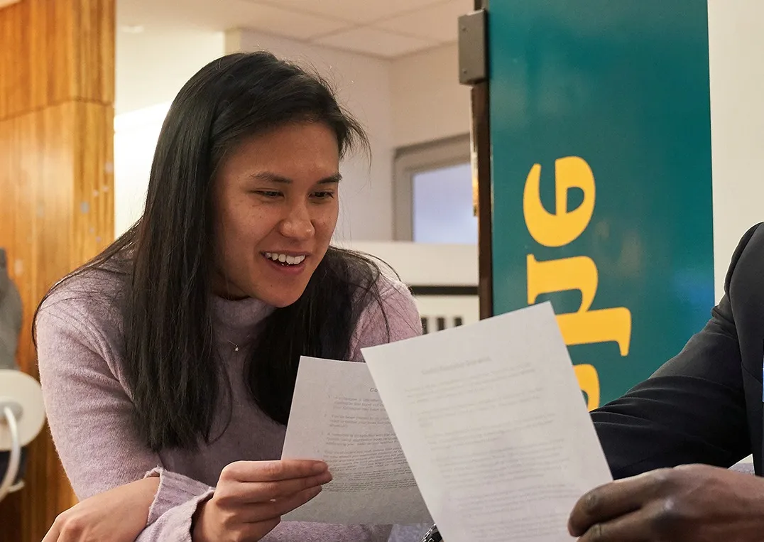 A woman smiling as she reads through paperwork at a Back on My Feet event