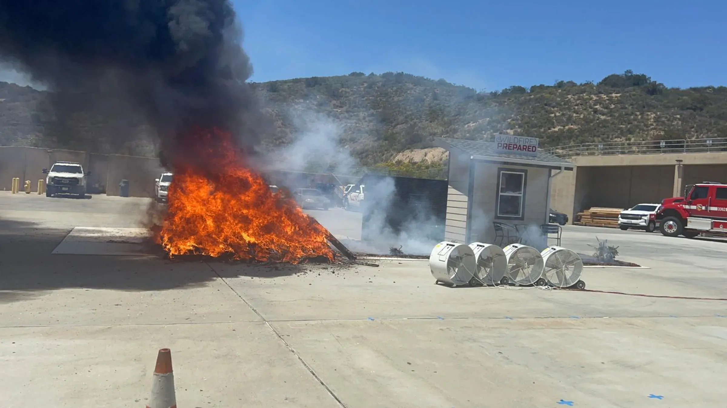 Flames and black smoke rising from the controlled burn beside the test house at the IBHS wildfire research facility