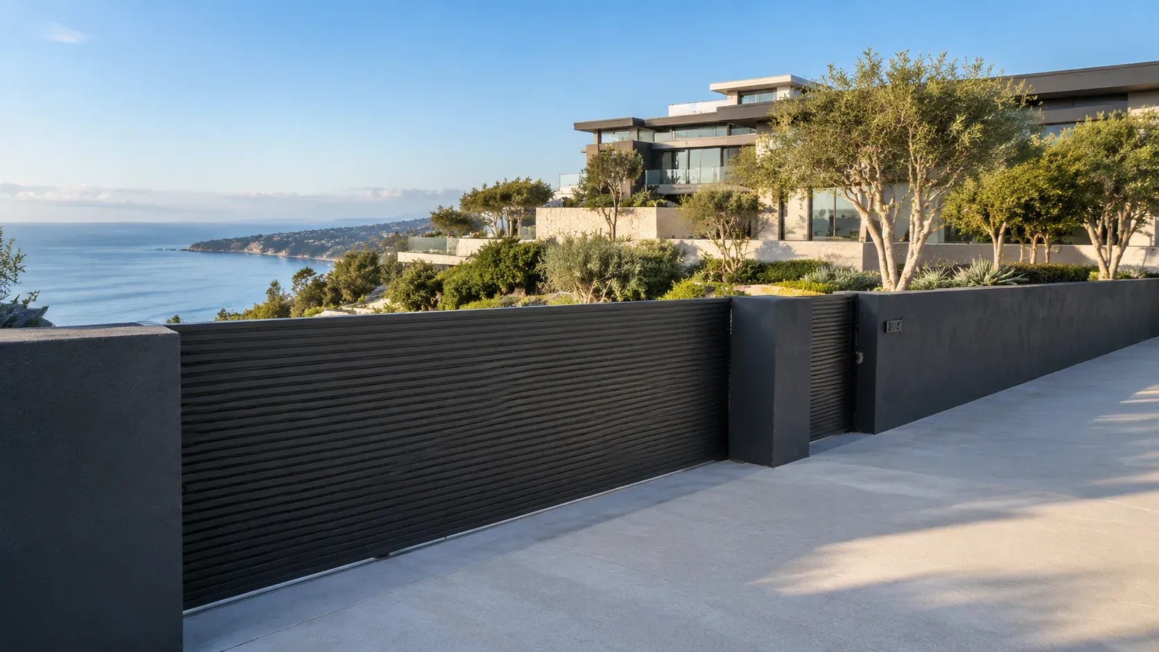 A clifftop Southern California home behind a dark aluminum fence, with the coastline beyond