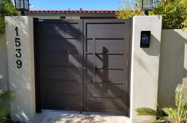 Dark aluminum gate and fence run against a stucco wall