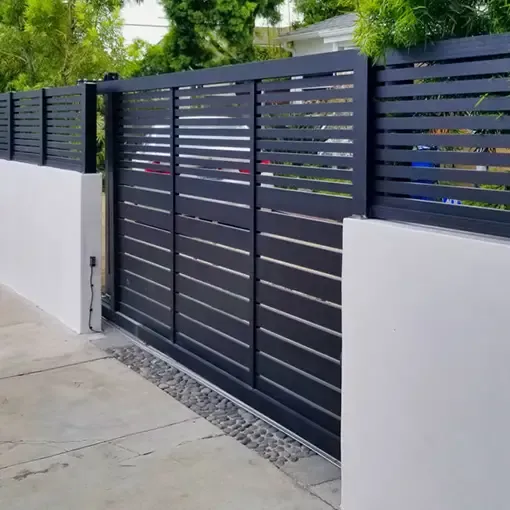 A dark horizontal-slat aluminum driveway gate between white stucco walls