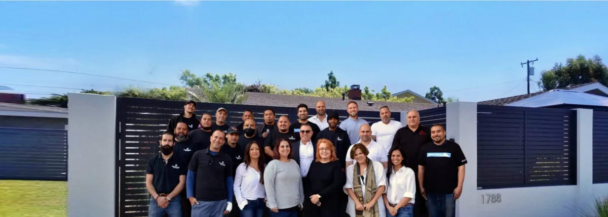 The Mulholland Brand team photographed together in front of one of their aluminum driveway gates