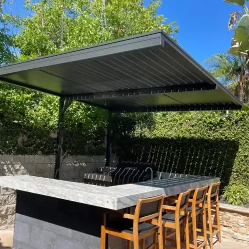 A dark aluminum pergola shading an outdoor dining table and chairs