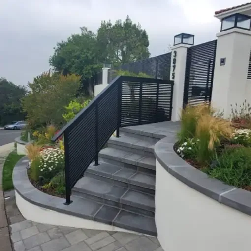 Dark aluminum railings running alongside a landscaped stone staircase