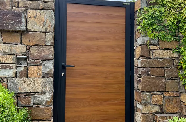 Wood-like aluminum pedestrian gate in a stone wall