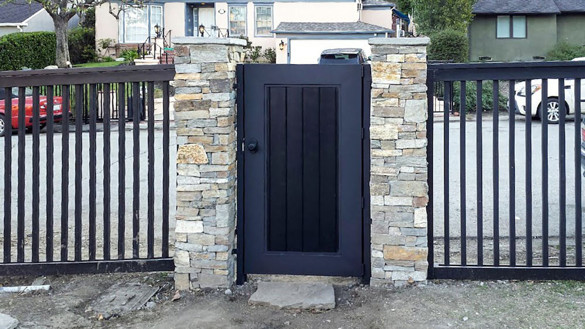Black wood entry gate with side fencing